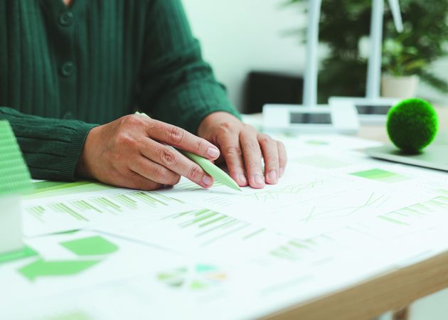 Eco-friendly,Business,Concept,With,Hand,Analyzing,Financial,Charts,And,Green